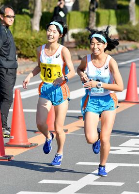 ２位から１位に順位を上げた白鴎足利の３区・梅村（左）が４区・平田にたすきを渡す＝佐野市運動公園周回コース