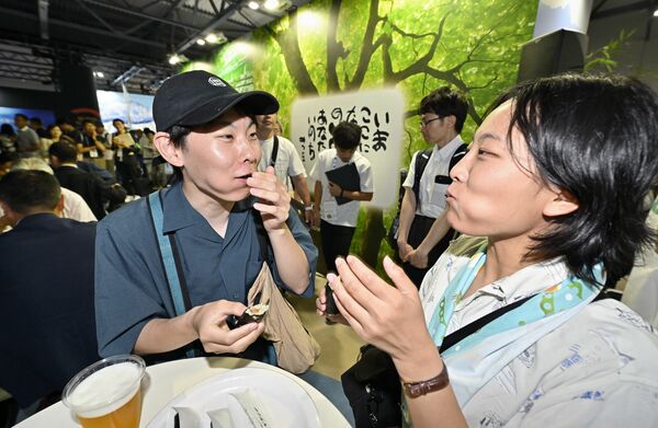 本県ブースの限定ビールや日光社参巻を食べ笑顔を見せる来場客
