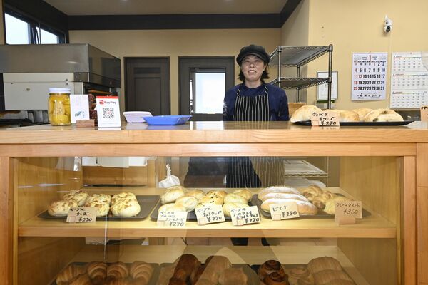 約20種類のパンが並ぶ店頭と店長の鈴木さん