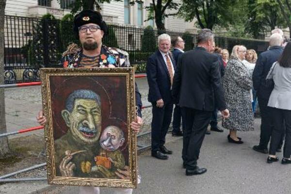 12日、ドイツ・ベルリンのロシア大使館前でプーチン氏の風刺画を掲げるセミョーン・スクレペツキー氏(同氏のテレグラムから・共同)
