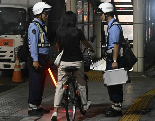 自転車を呼び止めて運転者に声をかける警察官＝８月上旬、宇都宮市