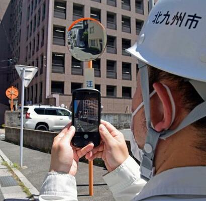　点検のためカーブミラーの写真を撮影する北九州市職員＝７月、北九州市