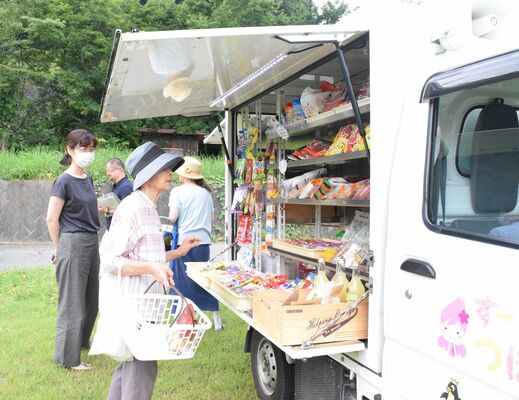 移動スーパーで商品を選ぶ近隣住民