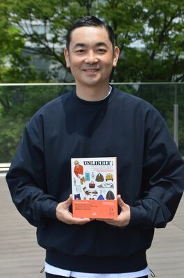 自身が集めたありそうでないアイテムを紹介するパーソナルブックを手にする中田さん