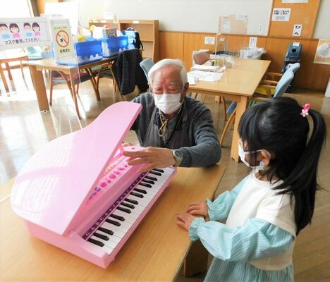 壊れて音が出なくなったおもちゃのピアノの状態を確認する長谷川さん（左）