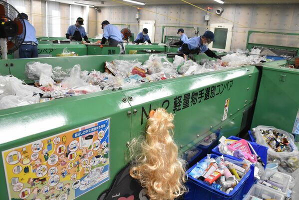 プラ容器の選別などを行う小山広域保健衛生組合の南部清掃センター。コンテナ脇に選別された空き缶、スプレー缶などが積まれている＝４月下旬、野木町