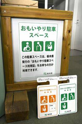 おもいやり駐車スペースを示す看板と利用証＝12月上旬、県庁