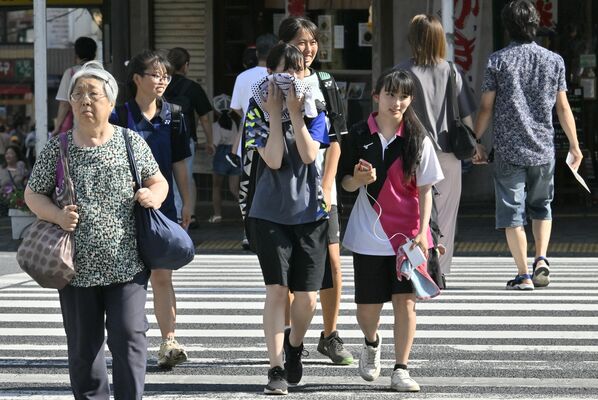 タオルで汗を拭くなどして歩く人たち＝７日午後３時30分、宇都宮市馬場通り１丁目
