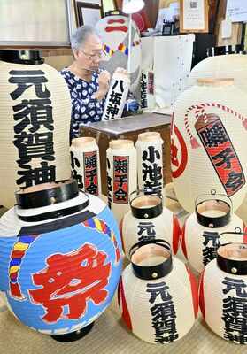 ちょうちんが並ぶ作業場で筆を握る田中さん＝５日午前10時35分、栃木市藤岡町新波