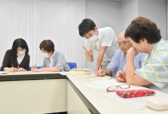堀野主任主事（中央）の指導を受けながら古文書を読み解く市民学芸員たち