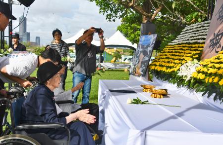 献花台の前で手を合わせる廖淑霞さん(手前)=7日、台湾南部・高雄市(共同)