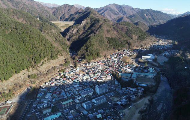 日の光が差し始めた町並み。山の影がくっきり見える。日の出時刻から２時間がたっていた＝２０２２年12月12日午前８時50分、日光市足尾地域中心部、ドローンから