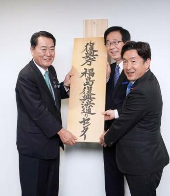 「福島復興浜通りセンター」の開所式で看板を掛ける牧野復興相(左)=24日午後、福島県双葉町