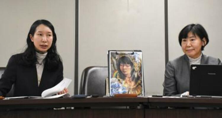 記者会見する原告側の代理人弁護士。中央の絵は原告の自画像=20日午後、東京・霞が関の司法記者クラブ