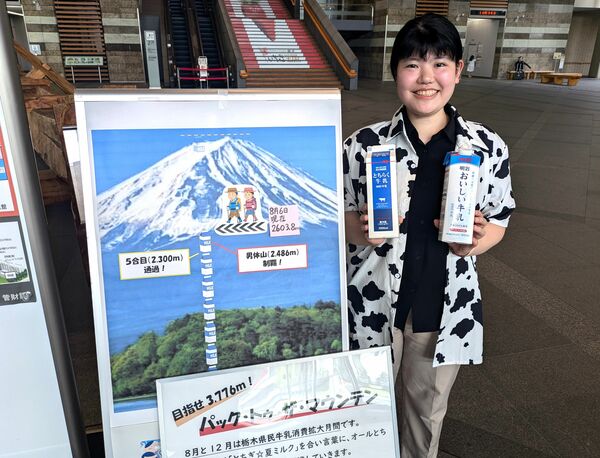 「パック・トゥ・ザ・マウンテン」の看板をPRする畜産振興課職員=8月上旬、県庁ロビー