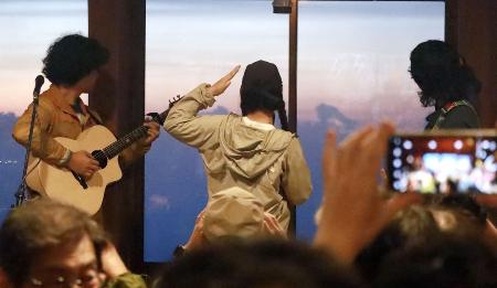 　ライブ中、夕焼けに染まった北アルプスの雲海を見つめる「スーパー登山部」のメンバーたち＝２０２５年８月、北アルプス白馬岳山頂付近の白馬山荘