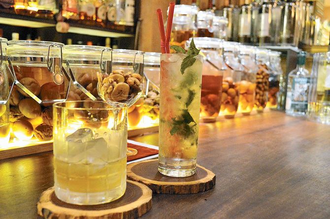 カウンターには梅酒（1200円から）や果実酒がずらり。アルマニャックの梅酒（左）、梅ラムモヒート（右）、自家製燻製ナッツ（奥）