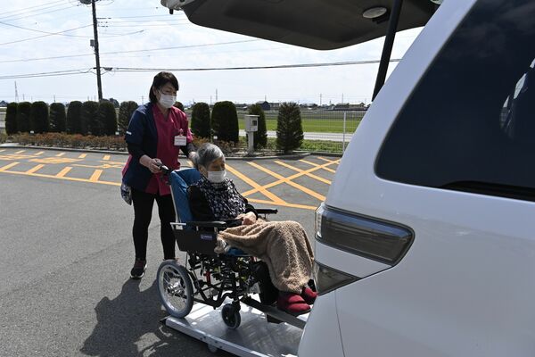 明るく声をかけながら車いすを福祉車両に移す野澤さん＝４月、上三川町上三川