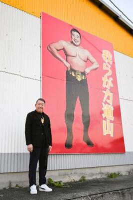 「プロレス殿堂館」の壁に掲げた力道山の肖像の前に立つ永田章一館長=2025年12月、熊本県天草市