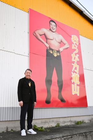 　「プロレス殿堂館」の壁に掲げた力道山の肖像の前に立つ永田章一館長＝２０２５年１２月、熊本県天草市