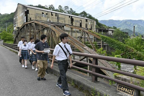 古河橋や製錬所跡など足尾の史跡を巡るふたば未来学園高の生徒ら＝25日午後、日光市足尾町赤倉