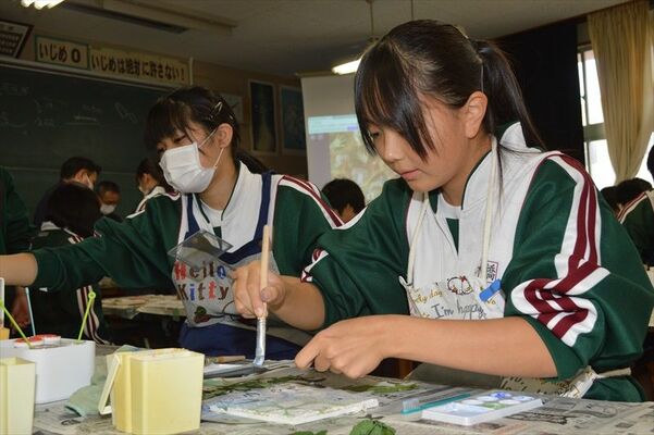 白い下地に色を付けてフレスコ画制作に取り組む生徒たち