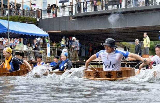 「松川タライ乗り競走」で、大きなタライに乗り込み川を下る参加者=5日午前、静岡県伊東市