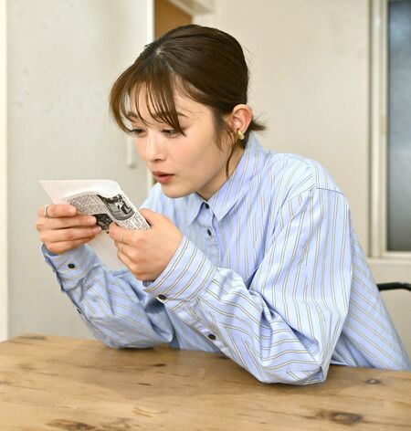 駅伝大会で区間賞を獲得し、本紙に登場した井上さん。当時の記事をまじまじと見つめる＝１月下旬、東京都内、森田大地撮影