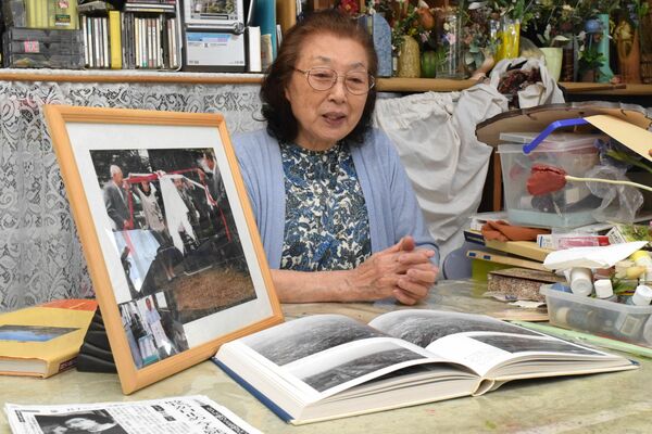 平和の礎の除幕式の写真を前に平和への思いを語る簗さん=6月上旬、宇都宮市駒生町
