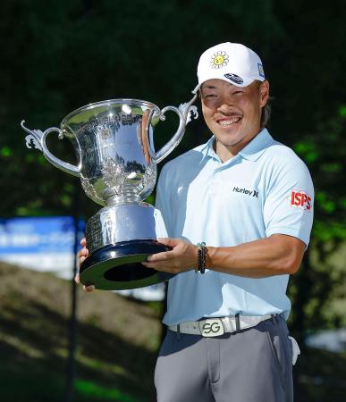 　通算９アンダーで優勝し、トロフィーを手に笑顔の藤本佳則＝茨木ＣＣ