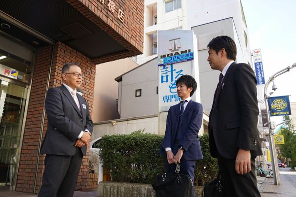 事業譲渡した崎尾社長（左）。足利銀行の担当者に現状を報告した後、玄関先で笑顔を見せた＝11月中旬、宇都宮市二荒町