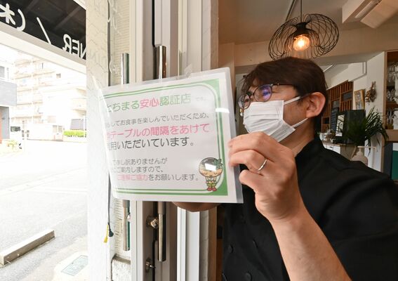 新型コロナの５類移行を受け「とちまる安心認証店」の張り紙を剥がすオーナーシェフ＝８日午前10時40分、宇都宮市下戸祭２丁目