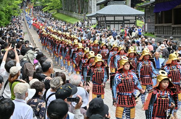 大勢の観衆の前を練り歩く鎧武者ら=18日午前11時25分、日光市山内