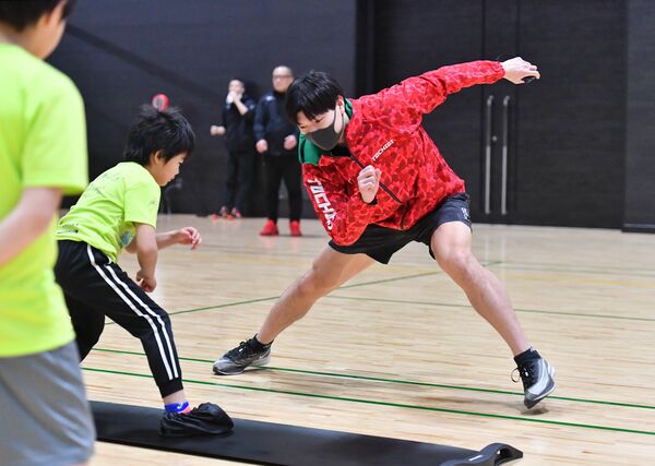 手本を見せながらスケートの滑りを教える小川（右）