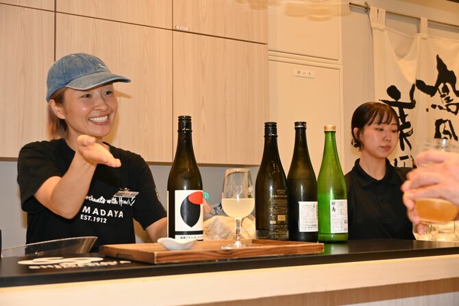 グラスに用意できた注文の酒を案内するスタッフ=29日夕、嶋田屋酒店宮みらい店角打ち店舗