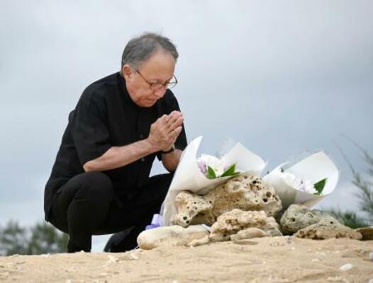 　沖縄県名護市辺野古沖での転覆事故の現場を臨む「瀬嵩の浜」で手を合わせる玉城デニー知事＝２１日午後