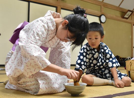 茶せんでお茶をたてる浴衣姿の参加者