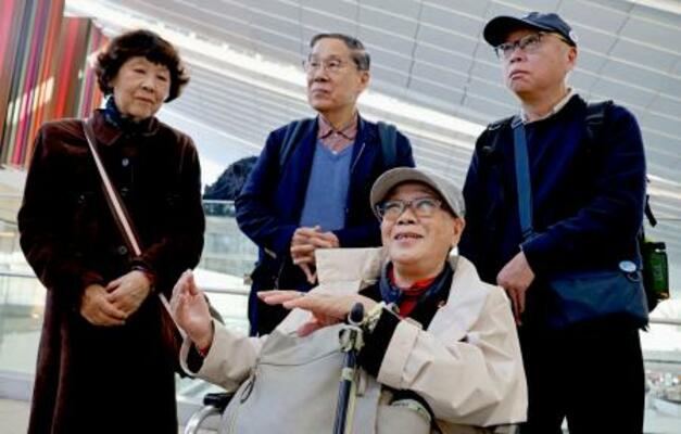 　米国への出発前、取材に応じる被爆者団体「長崎県被爆者手帳友の会」の代表団のメンバー。中央奥は朝長万左男さん＝２７日午前、羽田空港