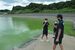 緑色に染まった会場の水面を見て驚き、写真に残す沖縄県の選手と監督＝10日午前、市貝町塩田