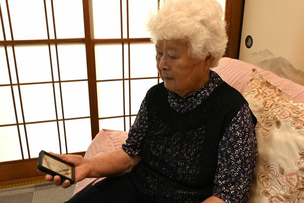 長兄正世さんの写真を手に平和への思いを語る田村さん=7月中旬、野木町野木