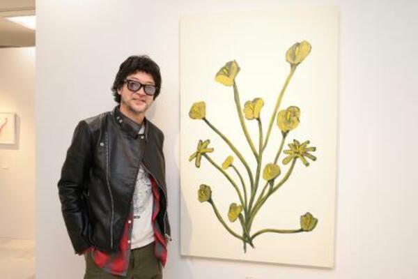 　お気に入りだという花の絵の横で写真に収まる浅野忠信
