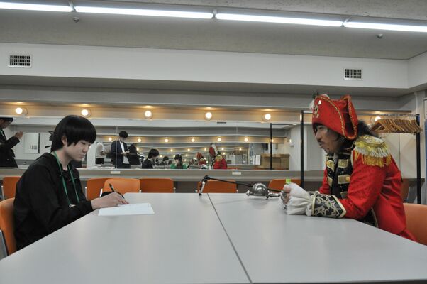 １日記者の佐川さん（左）のインタビューに応じる「歌う海賊団ッ！」のキャプテン☆うっちゃるさん＝１日午後、県総合文化センター、中村寛子撮影