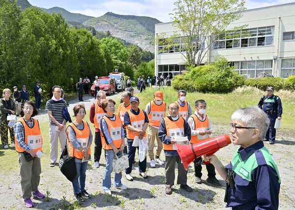 県の担当者(手前右)から訓練内容の話を聞く地域住民ら=13日午後0時45分、佐野市水木町、磯真奈美撮影