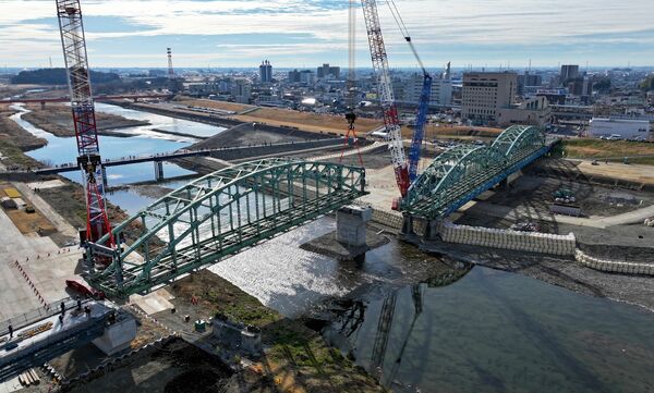 クレーンでつり上げられ下流側の橋脚に移設される中橋のアーチ=27日午前10時、足利市通2丁目、ドローンから