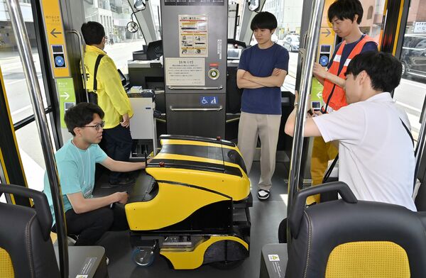 関係者が付き添う中、自動でLRTに乗車し待機するロボット=1日午前8時50分、宇都宮市東宿郷4丁目