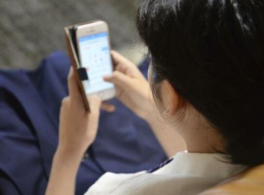 スマートフォンの画面を見る若者