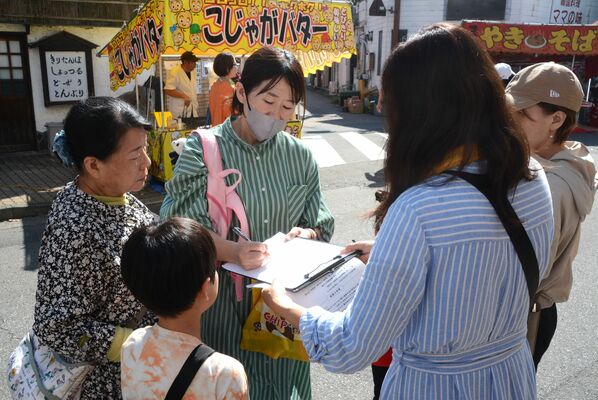 イベントの来場者に署名を呼びかける佐々木さん（手前右）＝12日午前11時、前橋市