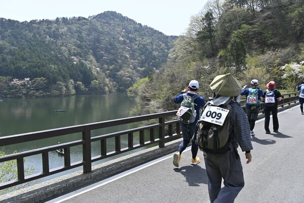 東古屋湖の景色を写真に収めながら歩く参加者