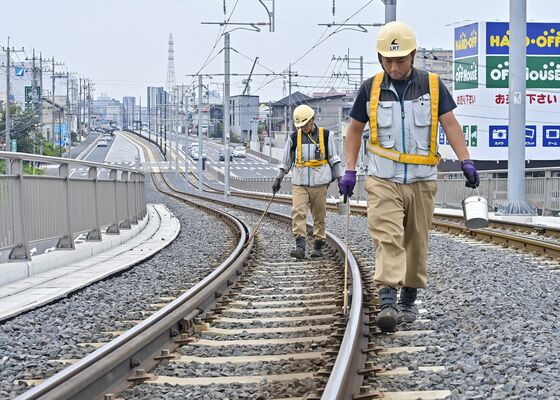 レールに潤滑油を塗る作業に当たる斎藤さん（右）と柳田さん＝22日午後１時30分、宇都宮市下平出町
