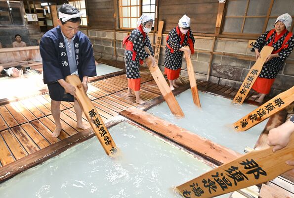 湯もみ唄に合わせ、板で湯をかき混ぜる保存会の会員たち＝29日午前11時５分、那須町湯本